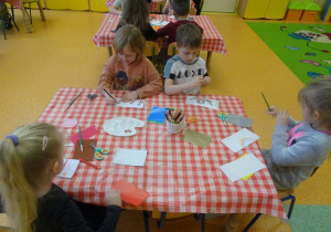 Czwórka dzieci projektu swój banknot, rysują kredkami.